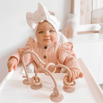 bébé manipule anneau de dentition rose clair beige