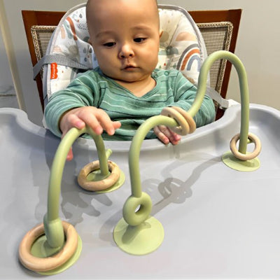 bébé s'amuse avec anneau de dentition vert beige